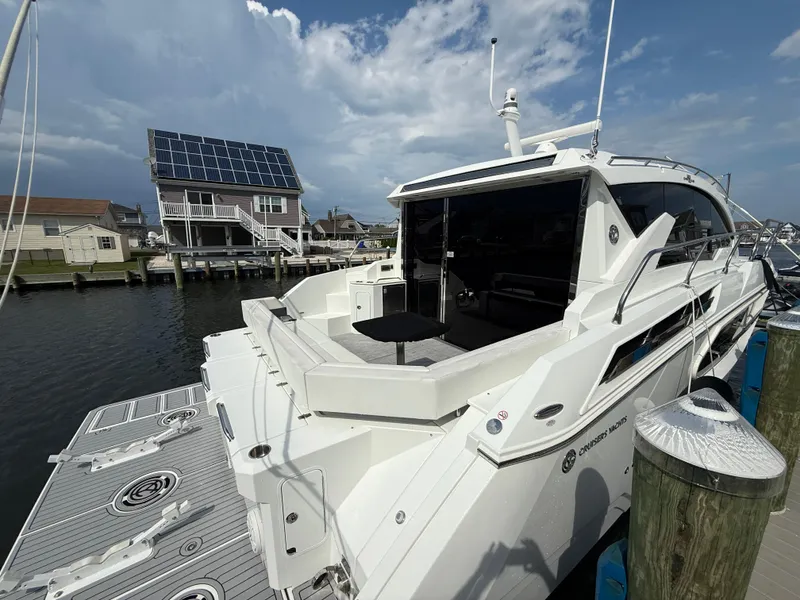 Slide: The Image of 2018 Cruisers Yachts 42 Cantius docked near waterfront homes under a cloudy sky. - 9