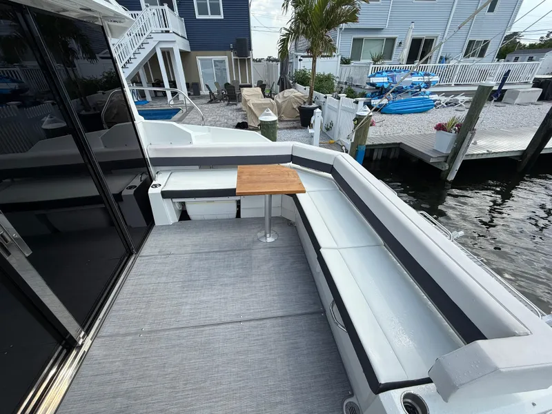Slide: The Image of 2018 Cruisers Yachts 42 Cantius deck with seating and table, docked by waterfront homes. - 13