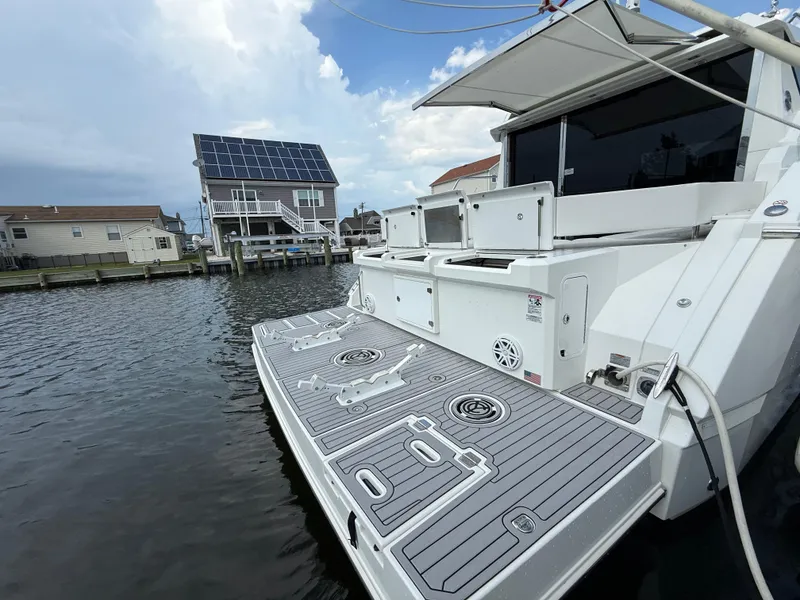 Slide: The Image of 2018 Cruisers Yachts 42 Cantius docked near waterfront homes under a cloudy sky. - 17