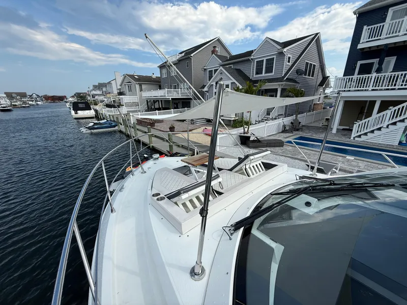 Slide: The Image of 2018 Cruisers Yachts 42 Cantius docked near waterfront homes under a partly cloudy sky. - 20