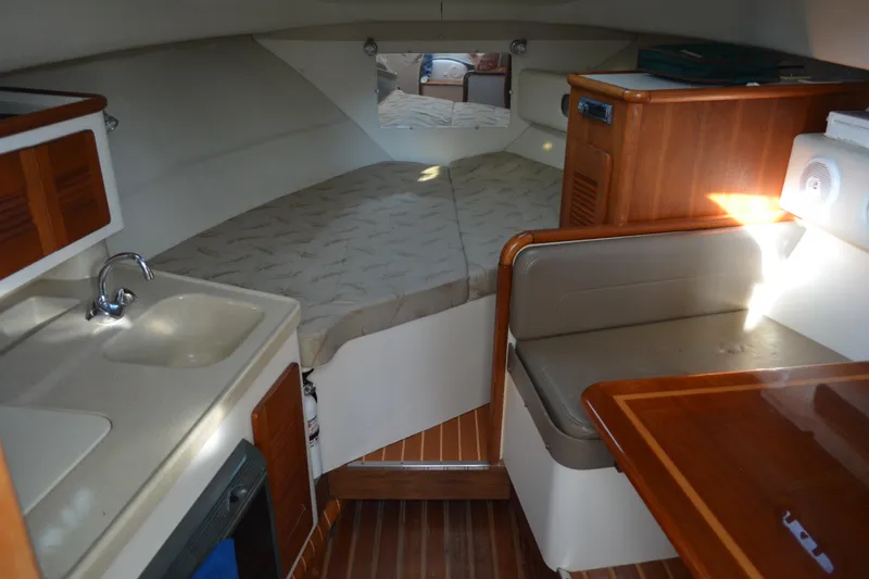 Slide: The Image of 2003 Pursuit 3000 Express cabin interior with kitchenette, seating, and bed. - 38