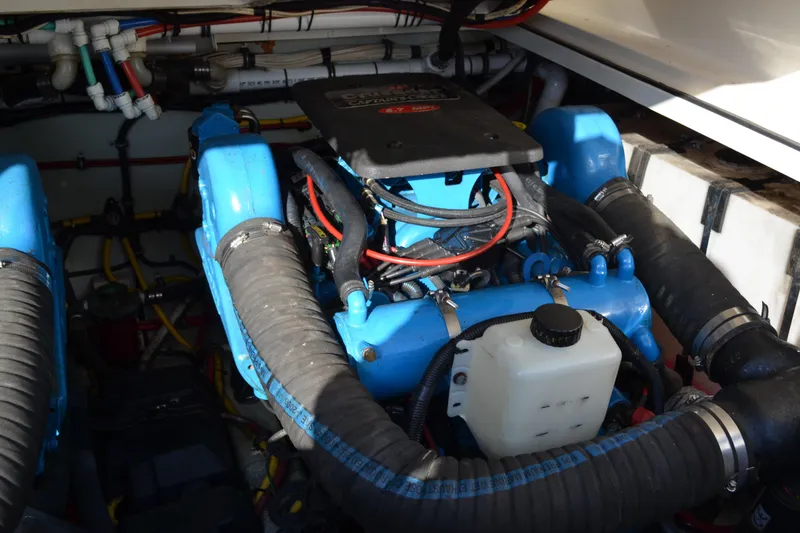 Slide: The Image of Engine compartment of a 2003 Pursuit 3000 Express boat, featuring blue components and hoses. - 58