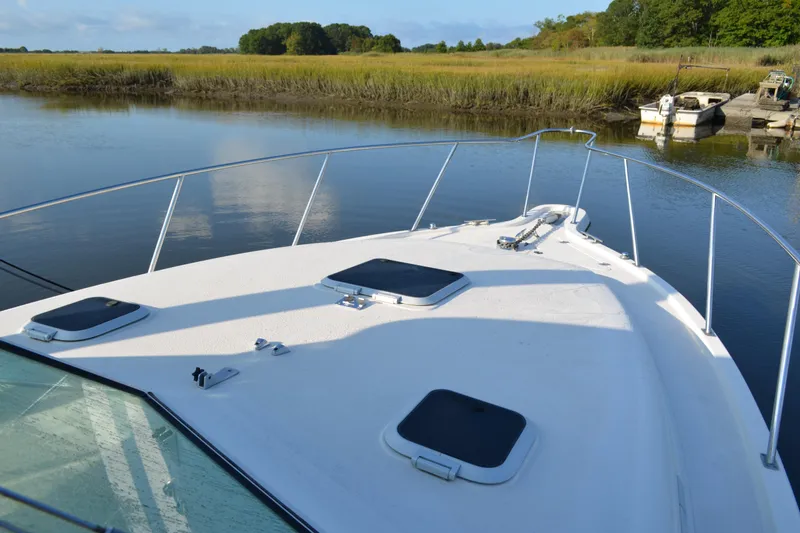 Slide: The Image of 2003 Pursuit 3000 Express boat on calm water, surrounded by lush greenery. - 10