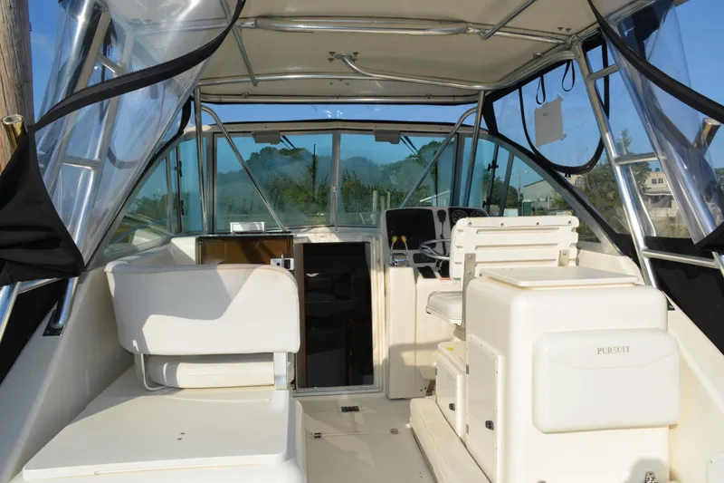 Slide: The Image of 2003 Pursuit 3000 Express boat interior with helm, seating, and clear enclosure. - 16
