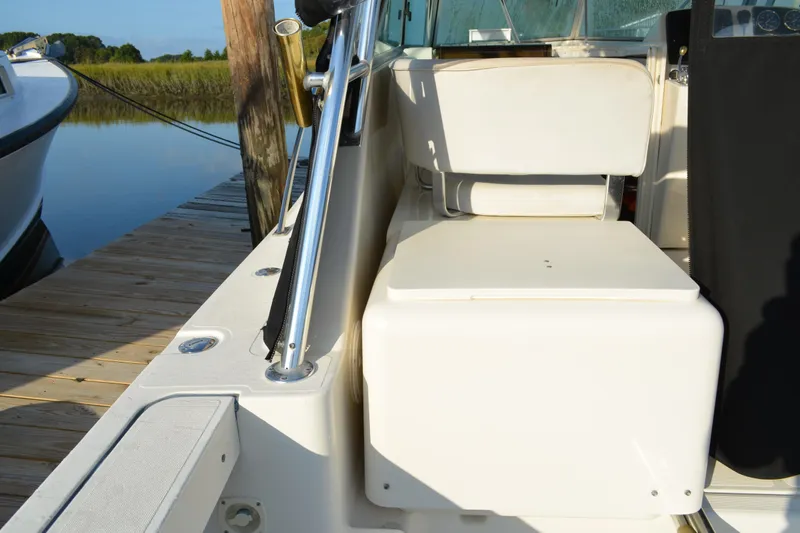 Slide: The Image of 2003 Pursuit 3000 Express boat interior with seating, docked by calm water. - 20