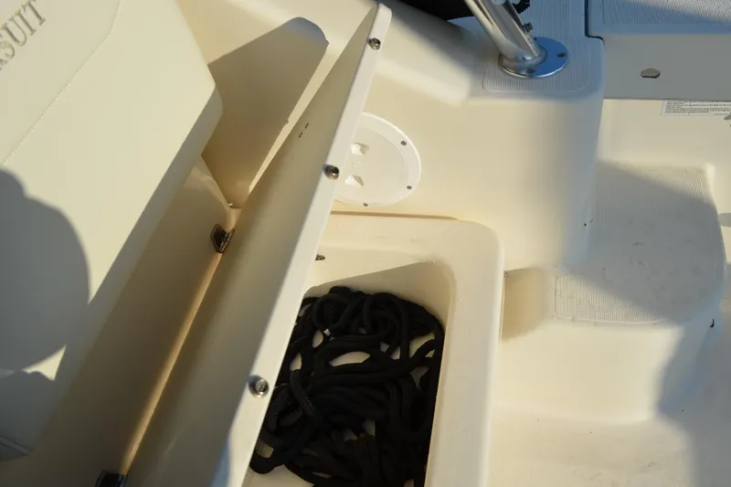 Slide: The Image of 2003 Pursuit 3000 Express boat storage compartment with coiled black rope. - 22