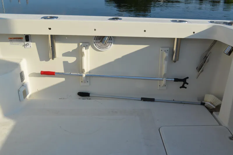 Slide: The Image of 2003 Pursuit 3000 Express boat deck with fishing rod holders and cleaning tools. - 23