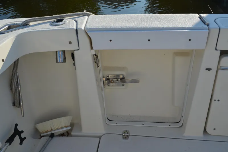 Slide: The Image of 2003 Pursuit 3000 Express boat interior with storage compartment and cleaning brush. - 24
