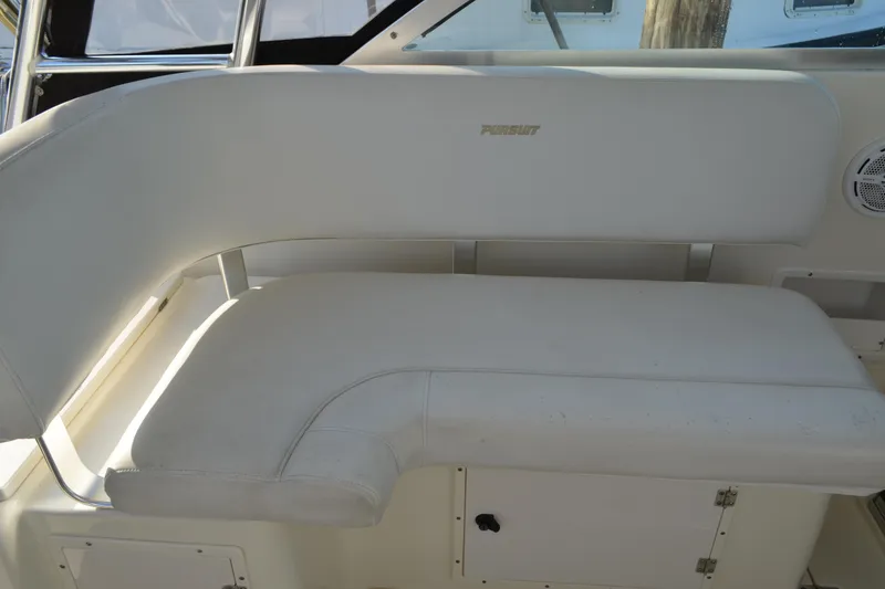 Slide: The Image of 2003 Pursuit 3000 Express boat interior with white cushioned seating. - 26