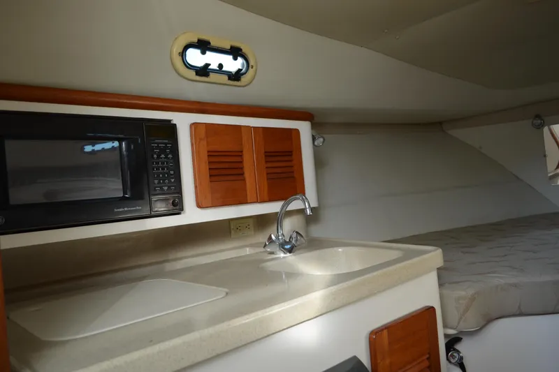 Slide: The Image of 2003 Pursuit 3000 Express boat interior with kitchenette, featuring a microwave and sink. - 40