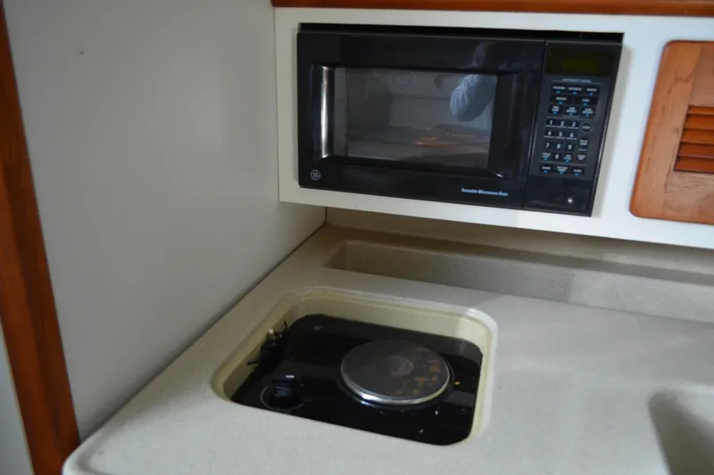 Slide: The Image of 2003 Pursuit 3000 Express boat kitchen with microwave and stove. - 42