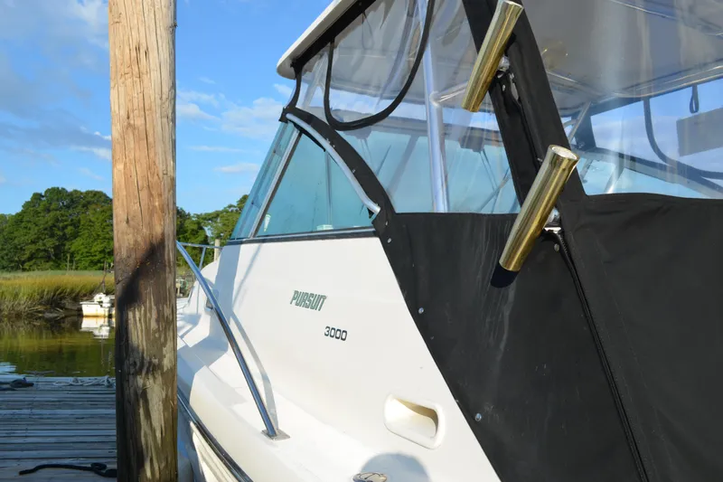 Slide: The Image of 2003 Pursuit 3000 Express boat docked by wooden pier, clear sky background. - 5