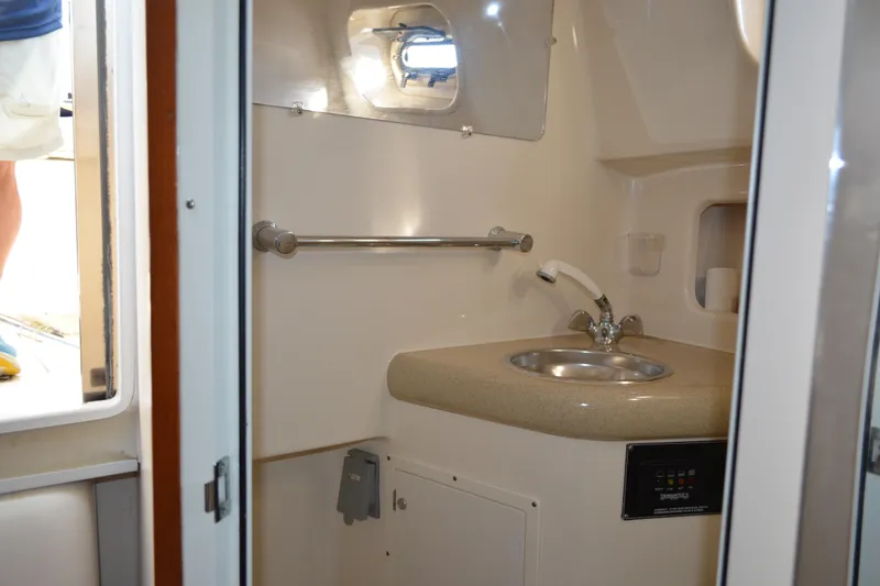 Slide: The Image of 2003 Pursuit 3000 Express boat bathroom with sink and porthole window. - 50