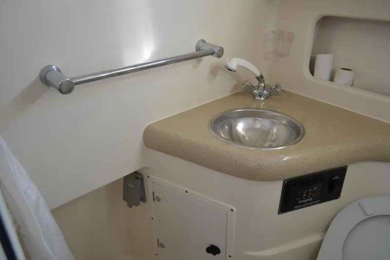 Slide: The Image of 2003 Pursuit 3000 Express boat bathroom with sink, faucet, and storage. - 53