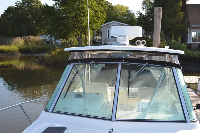 Slide: The Image of 2003 Pursuit 3000 Express boat docked near a serene lakeside cabin. - 13