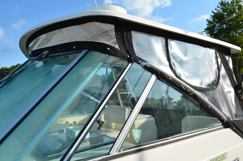 Slide: The Image of 2003 Pursuit 3000 Express boat with clear enclosure and windshield, docked under blue sky. - 7