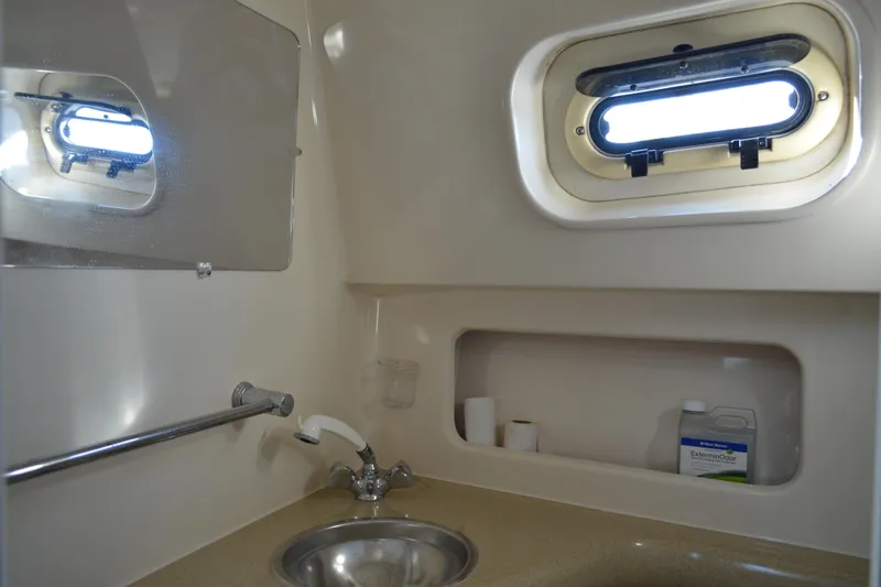 Slide: The Image of 2003 Pursuit 3000 Express boat bathroom with sink, window, and storage shelf. - 52