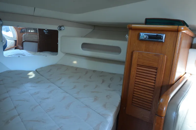 Slide: The Image of 2003 Pursuit 3000 Express cabin interior with bed and wooden storage unit. - 47
