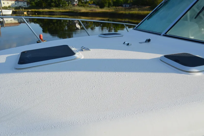 Slide: The Image of 2003 Pursuit 3000 Express boat deck with hatches, docked by calm water. - 9