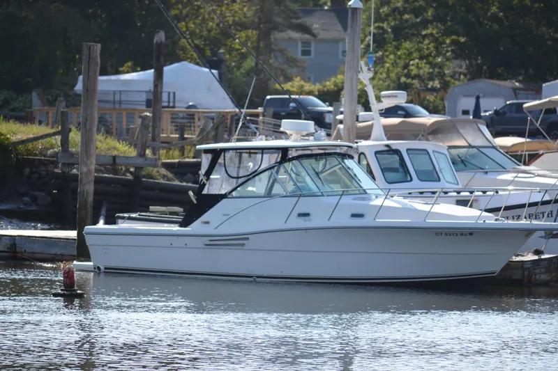 The Image of 2003 Pursuit 3000 Express boat docked at a marina, surrounded by other vessels. - 1