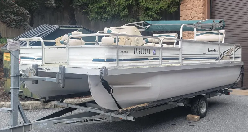 Slide: The Image of 1999 Landau 18 FISH pontoon boat on trailer, parked outdoors. - 1