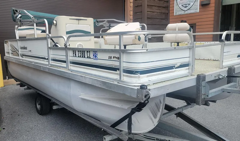 Slide: The Image of 1999 Landau 18 FISH pontoon boat on trailer, parked near service entrance. - 2