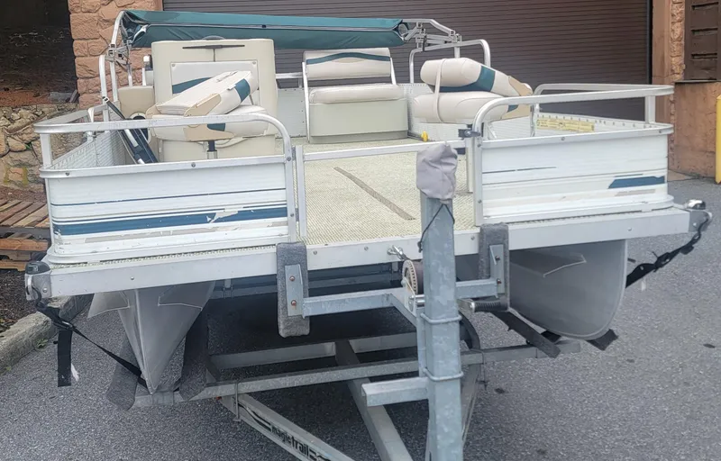 Slide: The Image of 1999 Landau 18 FISH pontoon boat on trailer, featuring cushioned seating and metal railings. - 3