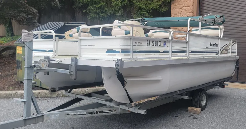 Slide: The Image of 1999 Landau 18 FISH pontoon boat on trailer, parked outdoors. - 4