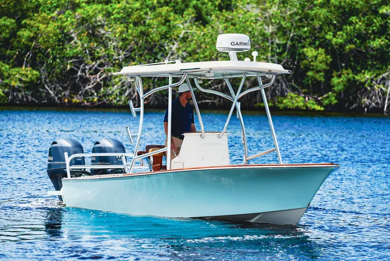 Slide: The Image of 1969 SeaCraft Potter hull boat on water, featuring dual engines and canopy, surrounded by lush greenery. - 2
