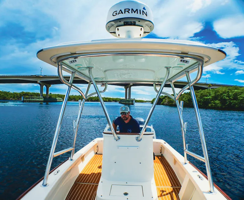 Slide: The Image of Man steering 1969 SeaCraft Potter hull boat under a bridge on a sunny day. - 9