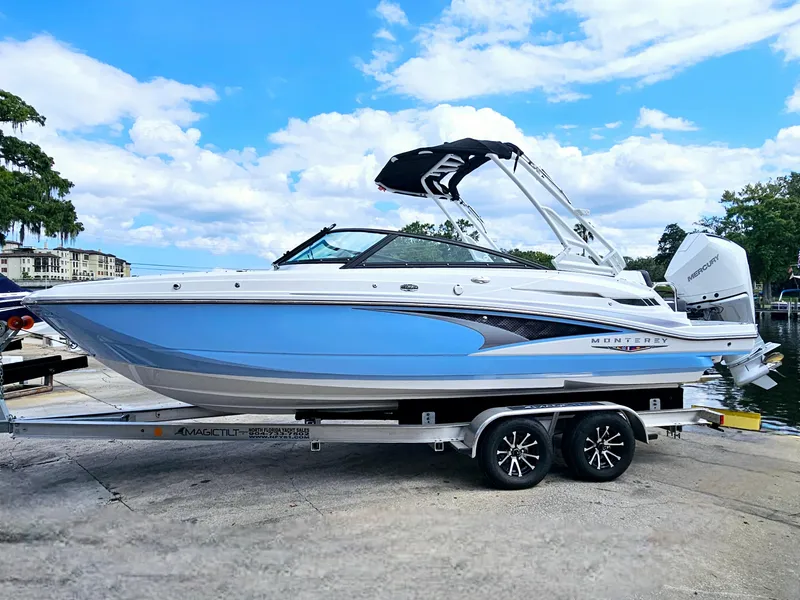 Slide: The Image of 2025 Monterey M-45 boat on trailer, blue and white design, parked near water. - 2