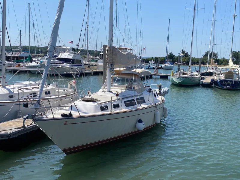 Slide: The Image of 1986 S2 11 Center Cockpit sailboat docked in a marina, surrounded by other boats. - 0