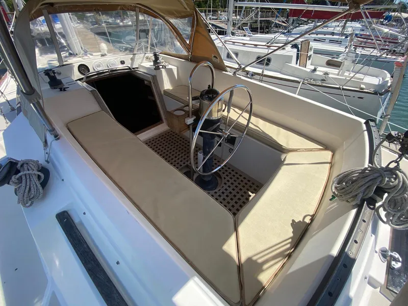 Slide: The Image of 1986 S2 11 Center Cockpit sailboat with beige seating and steering wheel, docked at marina. - 15