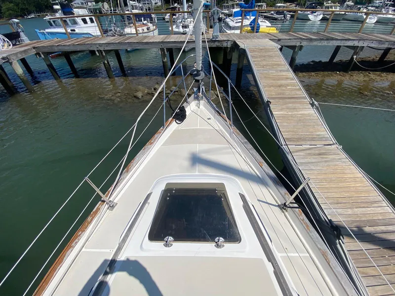 Slide: The Image of 1986 S2 11 Center Cockpit sailboat docked at a marina, viewed from the bow. - 19