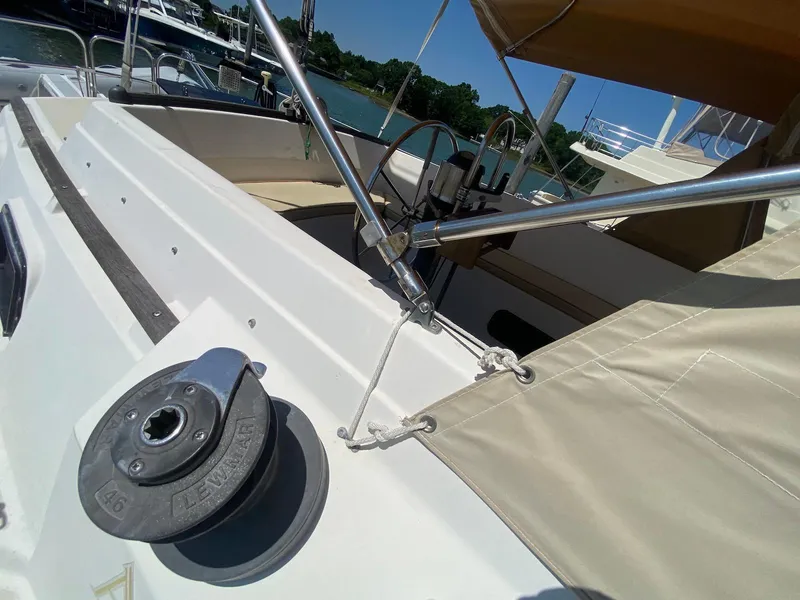 Slide: The Image of 1986 S2 11 Center Cockpit sailboat with winch and beige canopy, docked by the water. - 21
