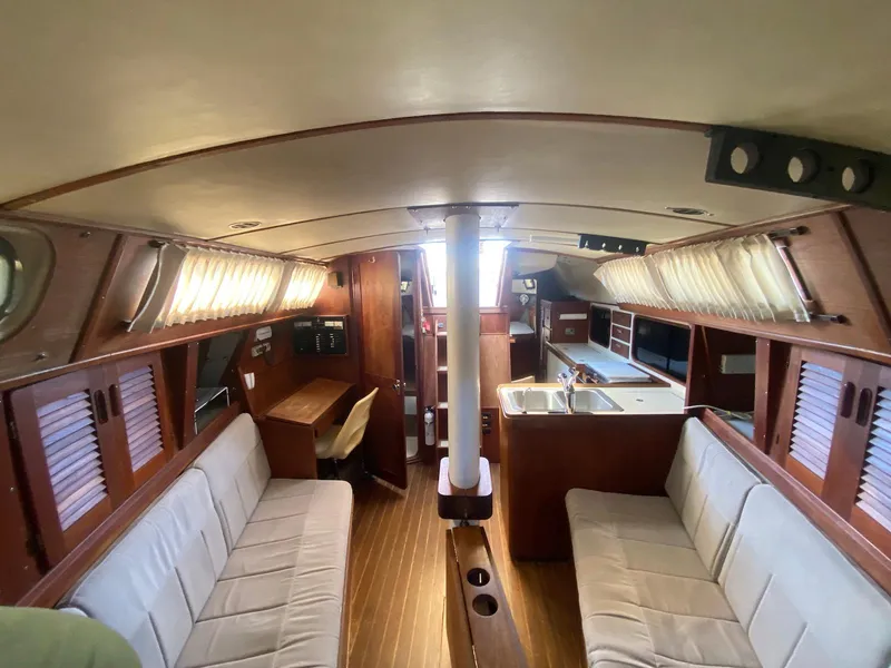 Slide: The Image of 1986 S2 11 Center Cockpit interior with wood finish, seating, and kitchenette. - 24