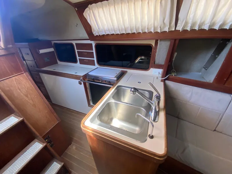 Slide: The Image of 1986 S2 11 Center Cockpit interior with sink, stove, and wooden cabinetry. - 26