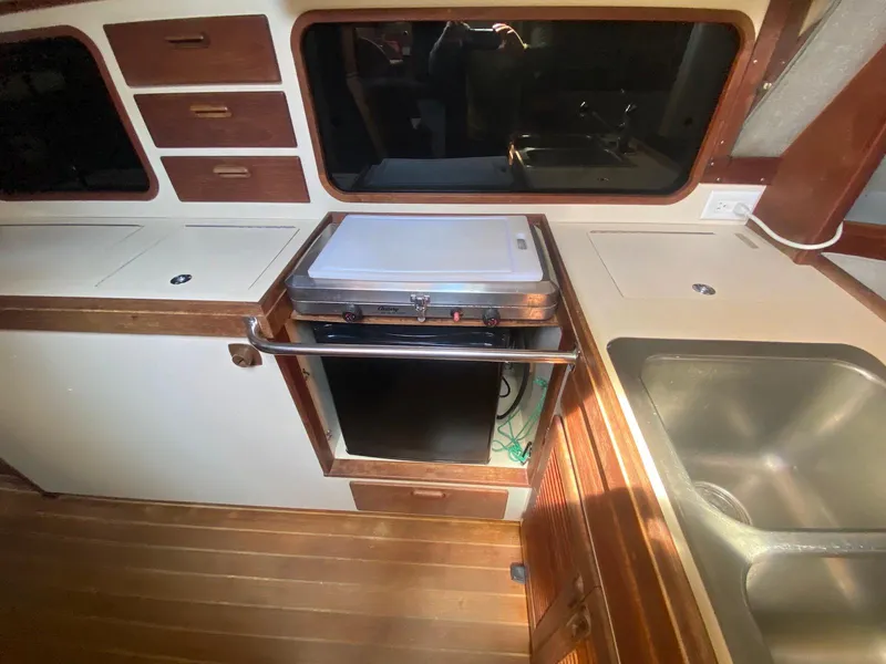 Slide: The Image of 1986 S2 11 Center Cockpit interior with stove, sink, and wooden cabinetry. - 27