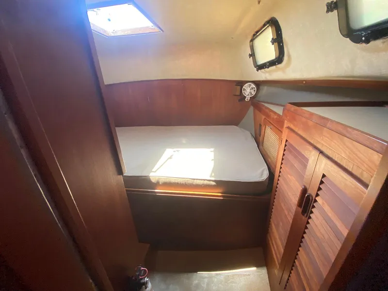 Slide: The Image of 1986 S2 11 Center Cockpit cabin interior with bed, wooden cabinets, and porthole windows. - 30