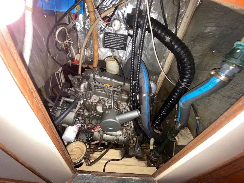 Slide: The Image of Engine compartment of 1986 S2 11 Center Cockpit sailboat with visible wiring and hoses. - 37