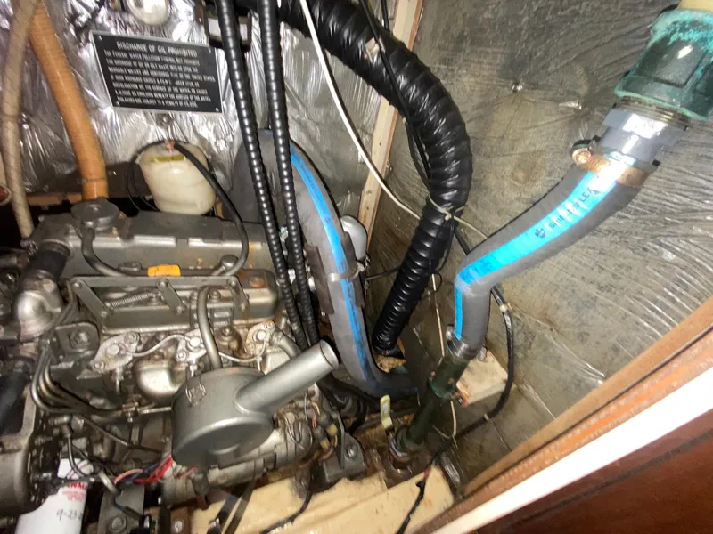Slide: The Image of Engine compartment of 1986 S2 11 Center Cockpit sailboat with visible hoses and components. - 39