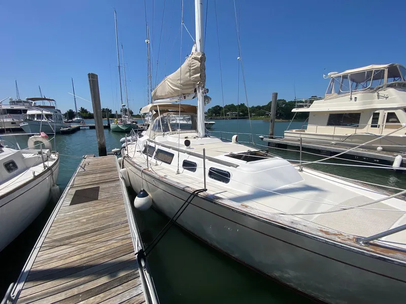 Slide: The Image of 1986 S2 11 Center Cockpit sailboat docked at marina under clear blue sky. - 7