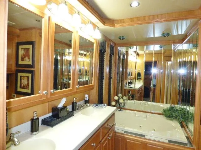 Slide: The Image of Luxurious bathroom with wooden cabinets, mirrors, and a jacuzzi tub in a Fantasy 19x112 model. - 14