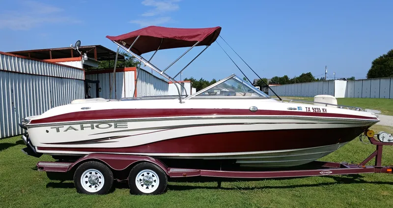 Slide: The Image of 2008 Tahoe Q7i boat with red and white design on a trailer, parked on grass. - 0
