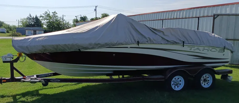 Slide: The Image of 2008 Tahoe Q7i boat covered on trailer, parked on grass near metal building. - 11