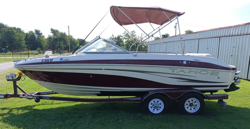 Slide: The Image of 2008 Tahoe Q7i boat on trailer with canopy, parked on grass near a metal building. - 3