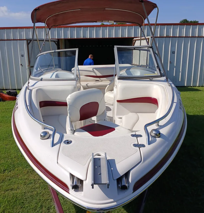 Slide: The Image of 2008 Tahoe Q7i boat with red and white interior, parked on grass near storage units. - 4