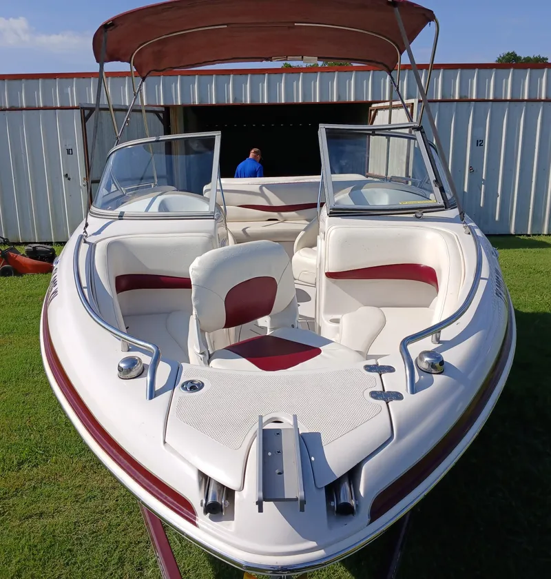 Slide: The Image of 2008 Tahoe Q7i boat with red and white interior, parked on grass near a storage unit. - 5