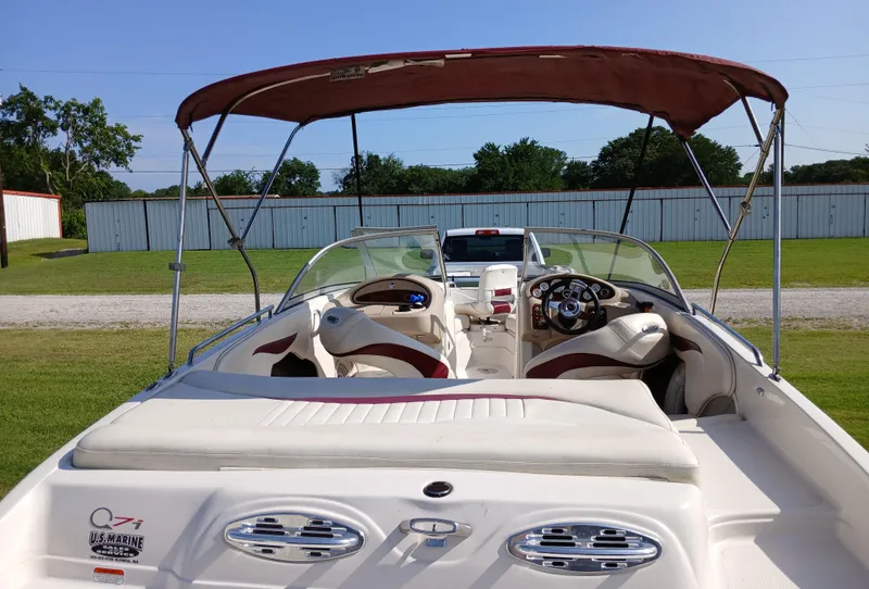 Slide: The Image of 2008 Tahoe Q7i boat with canopy, parked on grass, showcasing interior seating and steering wheel. - 7