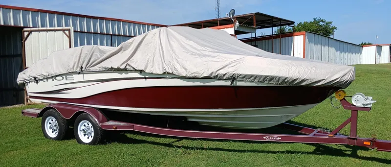 Slide: The Image of 2008 Tahoe Q7i boat on trailer, covered, parked on grass near metal building. - 9